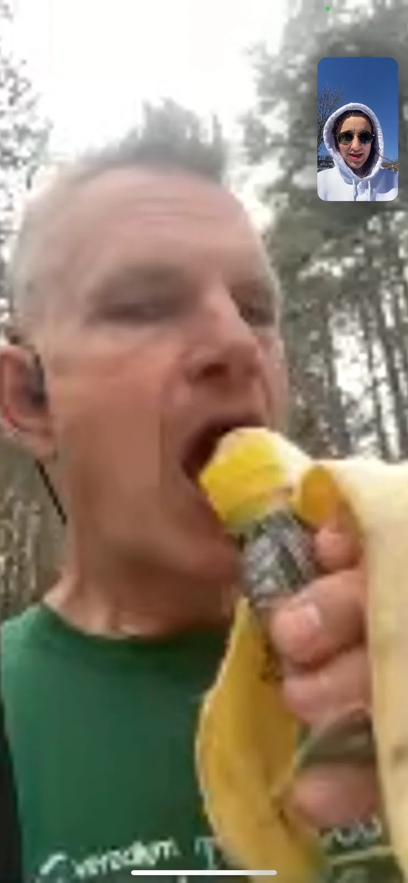 Kyle eating a banana mid-race while on FaceTime with his daughter, pickle juice in the other hand