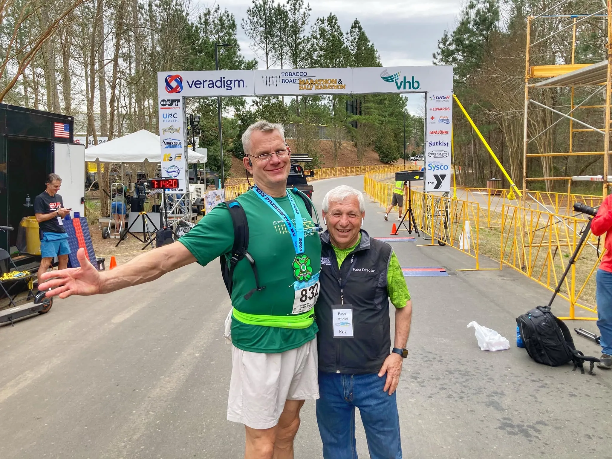 Kyle with Kazem Yahyapour standing under the Tobacco Road Marathon finish line arch