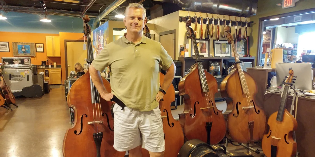 Kyle at Carter's Vintage Guitars in Nashville, standing among a row of double basses