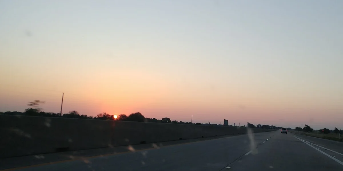 Sunrise over the interstate east of Dallas, seen through a car windshield