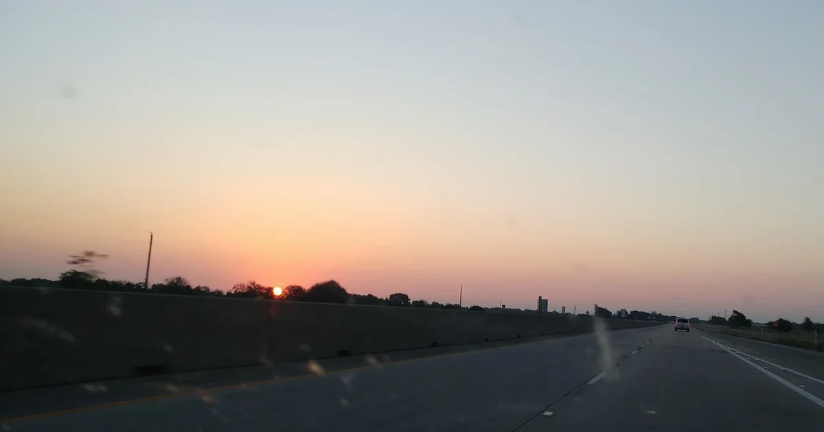 Sunrise over the interstate east of Dallas, seen through a car windshield